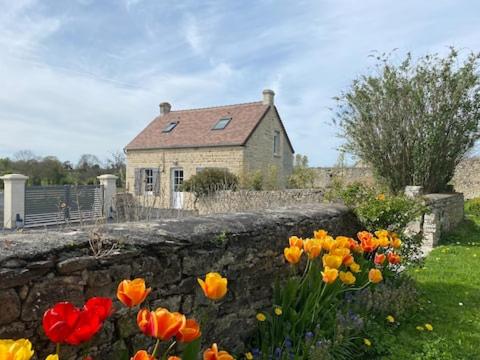 a stone wall in front of a house with flowers at Jolie maison pour 4 à 6 personnes in Ellon