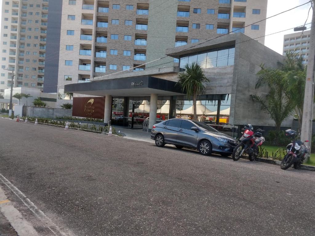 twee motorfietsen en een auto geparkeerd voor een gebouw bij Apartamento Salinas Premium Resort in Salinópolis