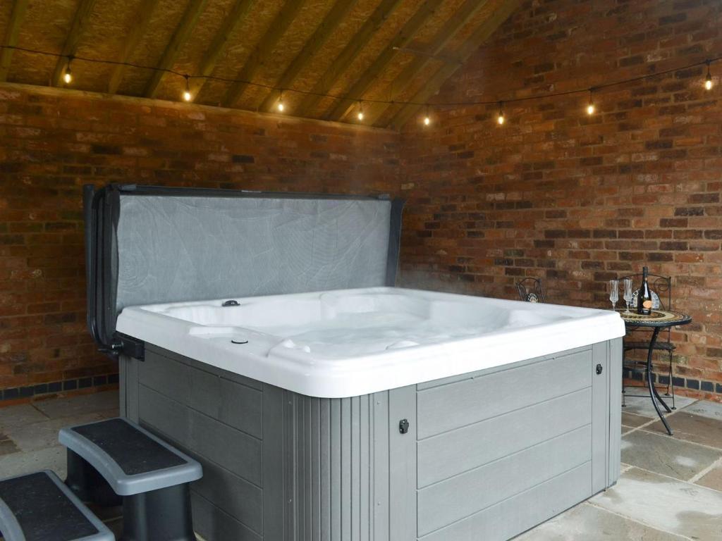 eine große weiße Badewanne in einem Zimmer mit Ziegelwand in der Unterkunft Cowslip - Uk13138 in Barnby Moor