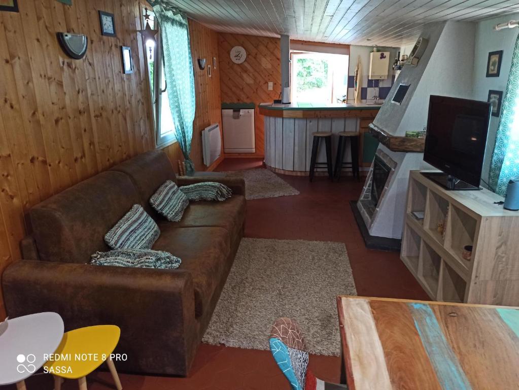 sala de estar con sofá marrón y cocina en Les abris de la hulotte, en Anould