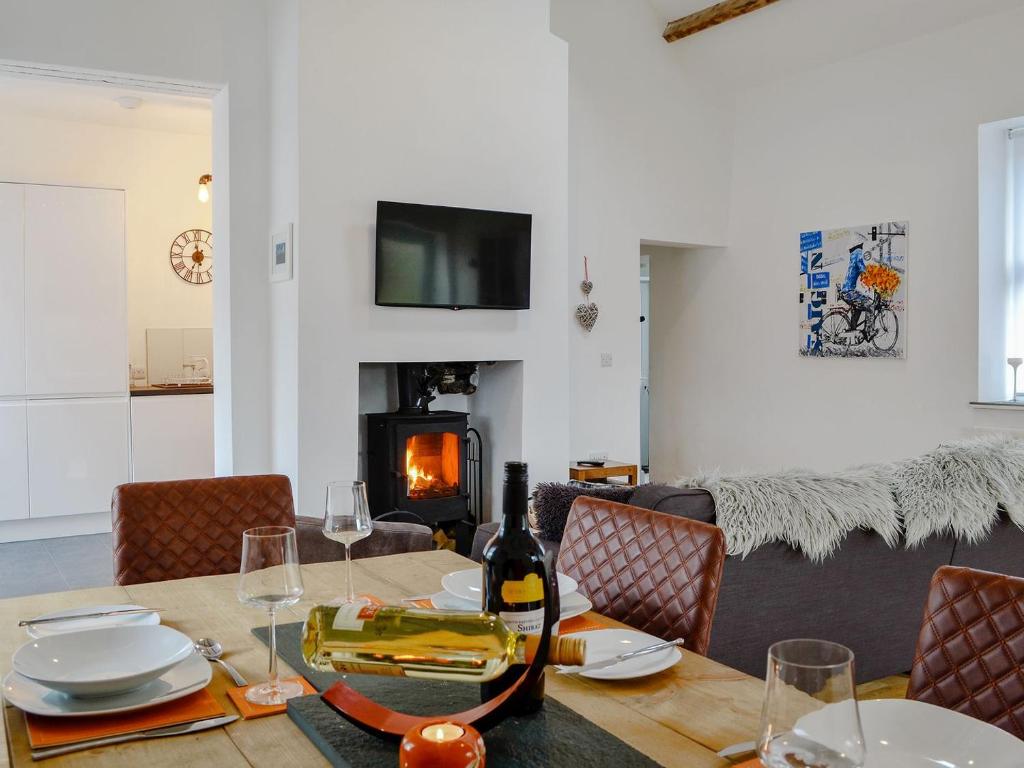 a dining room with a table with a bottle of wine at Katellen Cottage in Threlkeld