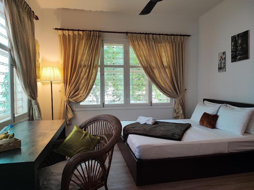 um quarto com uma cama, uma secretária e uma janela em Villa Papillon em Phnom Penh