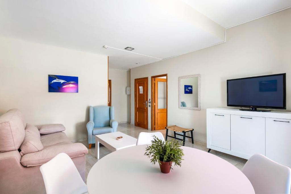 a living room with a table and a tv at Hotel Andrea´s in Los Cristianos