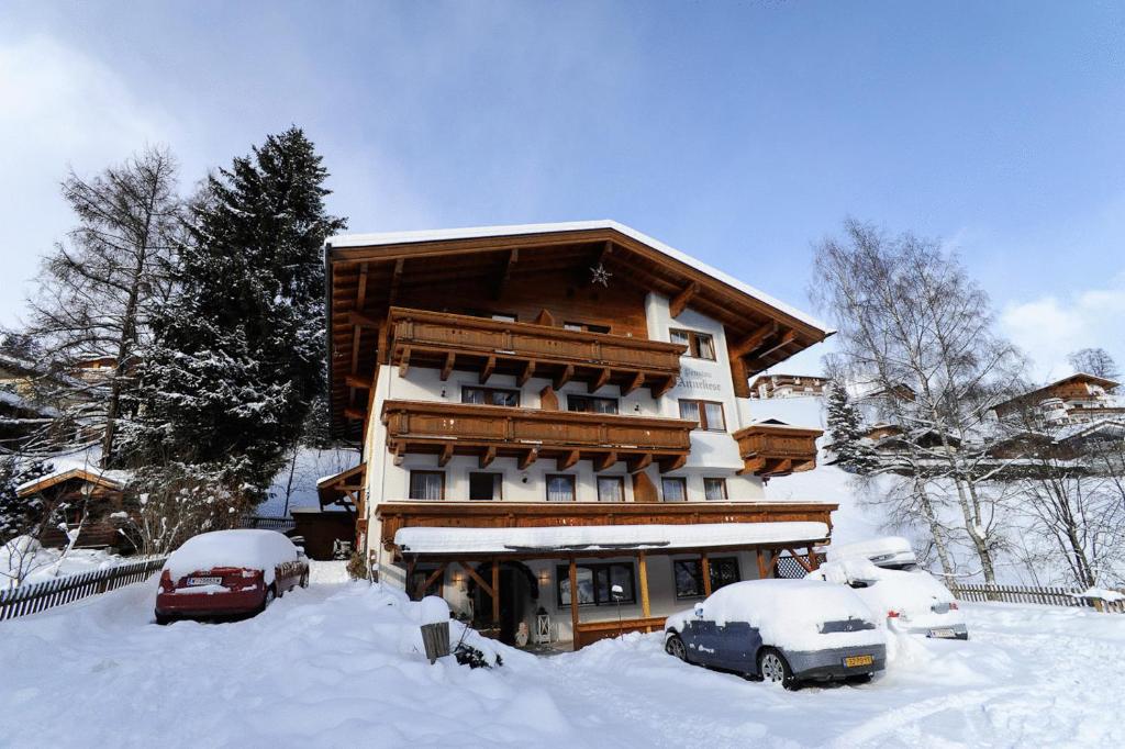 un bâtiment enneigé avec des voitures garées devant lui dans l'établissement Hotel Valerie, à Saalbach-Hinterglemm