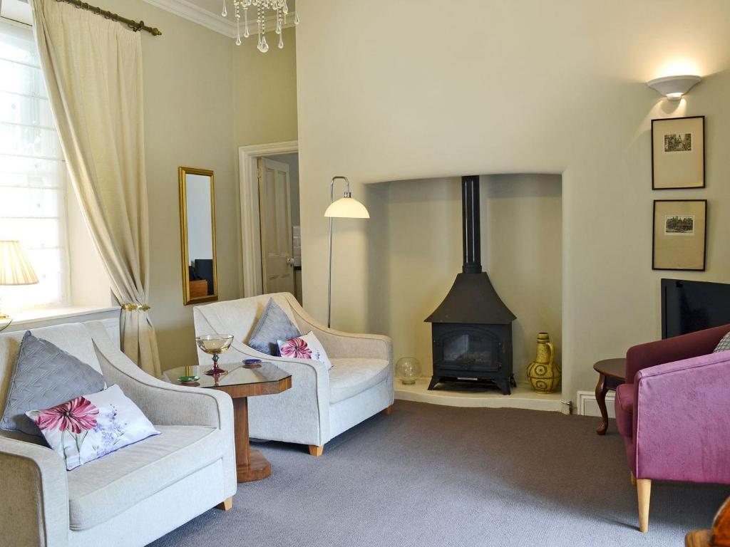 a living room with two chairs and a wood stove at Porters Lodge in Axminster