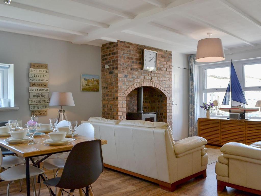 a living room with a white couch and a fireplace at Captains Cottage in Allonby