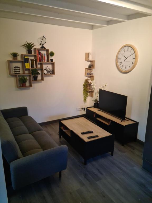 a living room with a couch and a table and a clock at Logement entier situé à Taponnat Fleurignac. in Taponnat-Fleurignac