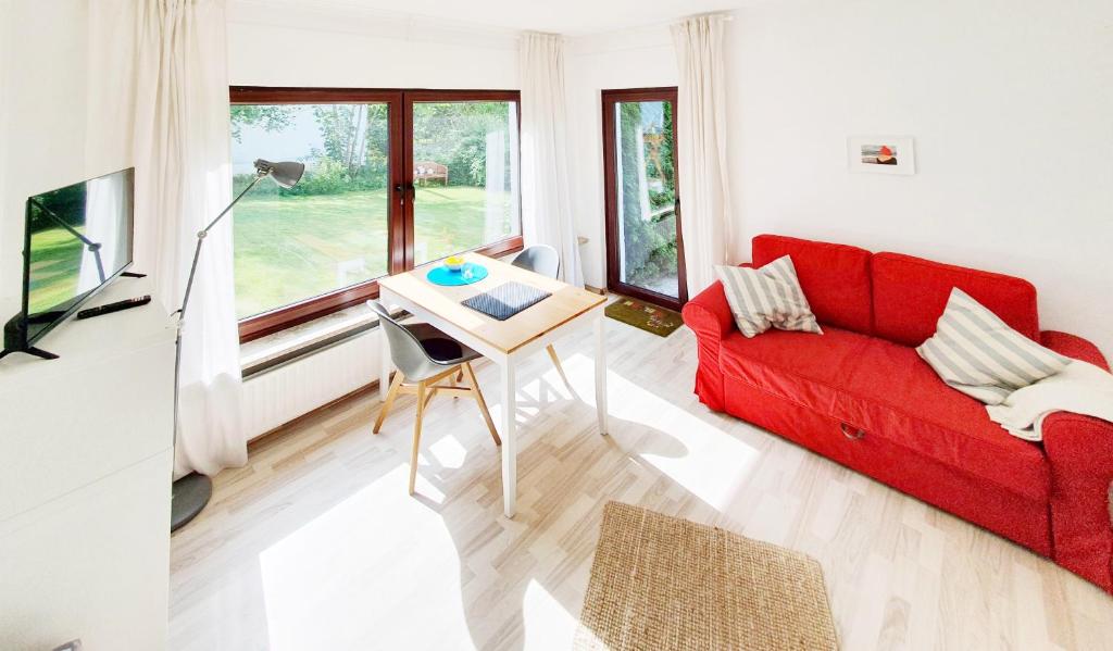 sala de estar con sofá rojo y mesa en Ferienwohnung Gartenblick - Idylle am Travetal en Bad Oldesloe