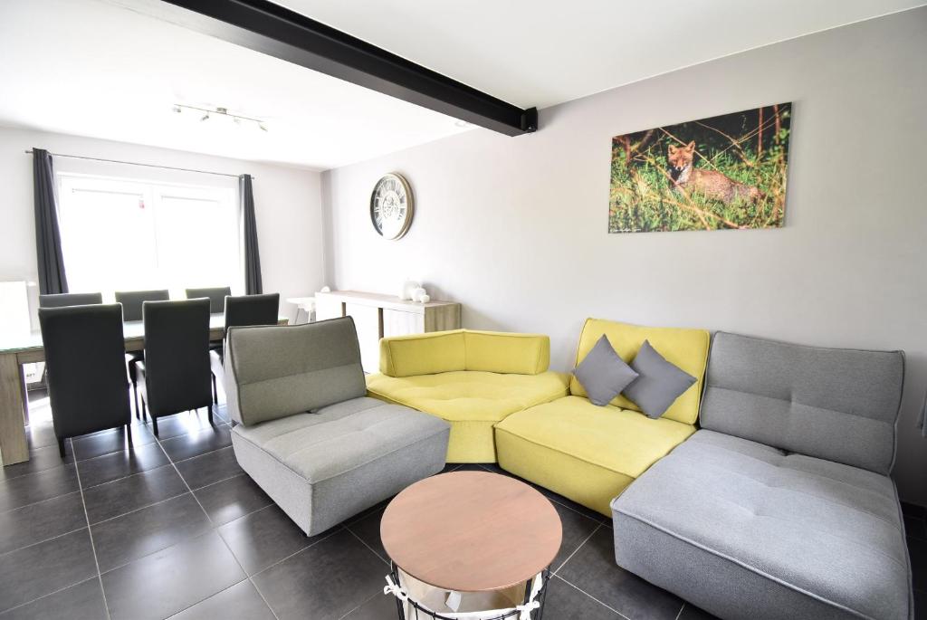 ein Wohnzimmer mit einem Sofa, Stühlen und einem Tisch in der Unterkunft Gîte Jod'en Campagne in Vaux-sur-Sûre