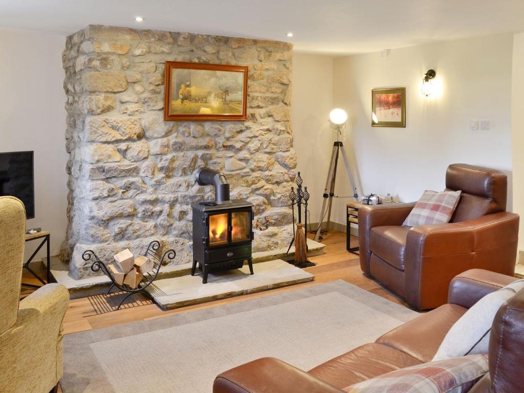 a living room with a stone wall with a fireplace at Broats Barn in Ingleton