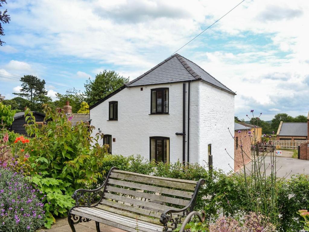 un banco en un jardín frente a una casa blanca en End Cottage en Tibthorpe