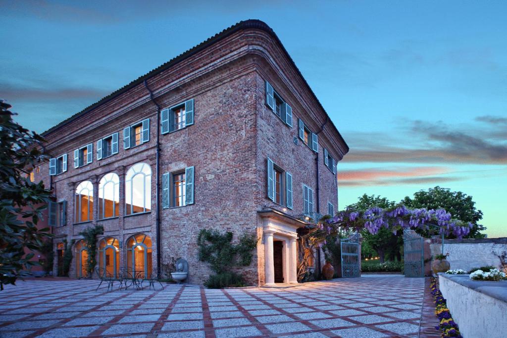 un gran edificio de ladrillo con un patio de piedra en Relais Sant'Uffizio Wellness & Spa, en Cioccaro