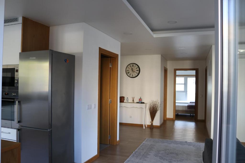 a kitchen with a refrigerator and a clock on the wall at Casa da Fonte Quente in Leiria