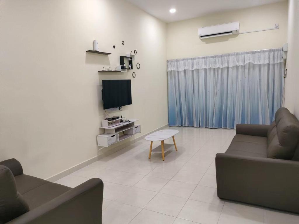a living room with a couch and a tv at My Homestay Sitiawan - Astronaut Space House 8 Pax in Sitiawan