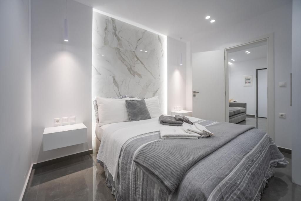 een witte slaapkamer met een bed met een marmeren hoofdeinde bij A casa nostra in Loutraki