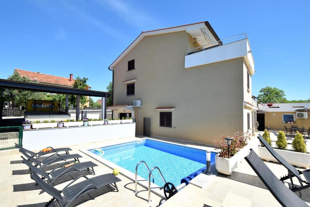 a villa with a swimming pool and patio furniture at Apartments Zrinka in Omišalj
