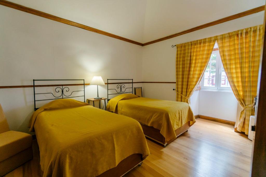 a bedroom with two beds and a couch and a window at Monte Ingles in Ponta Delgada
