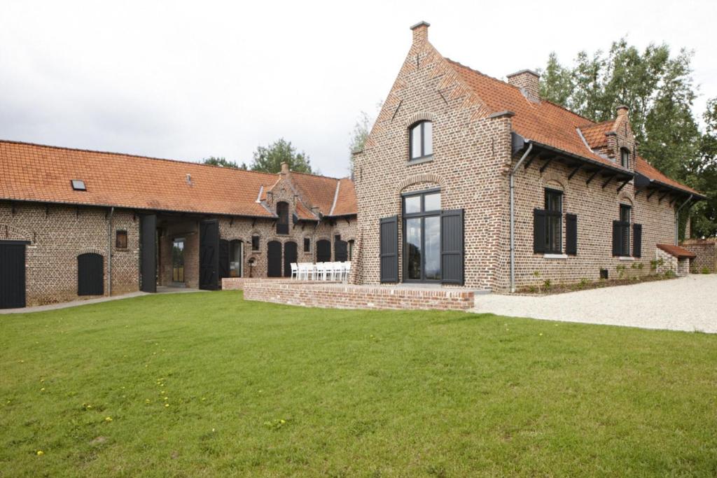 une grande maison en briques avec une grande pelouse dans l'établissement Vacation Home Landgoed de Monteberg, à Dranoutre