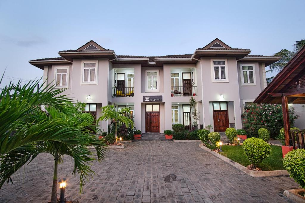 a large white house with a cobblestone driveway at The Highbridge Guest Lodge in Accra