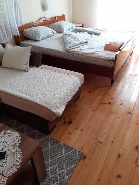two beds in a room with a wooden floor at Studio apartman jelena in Zaovine