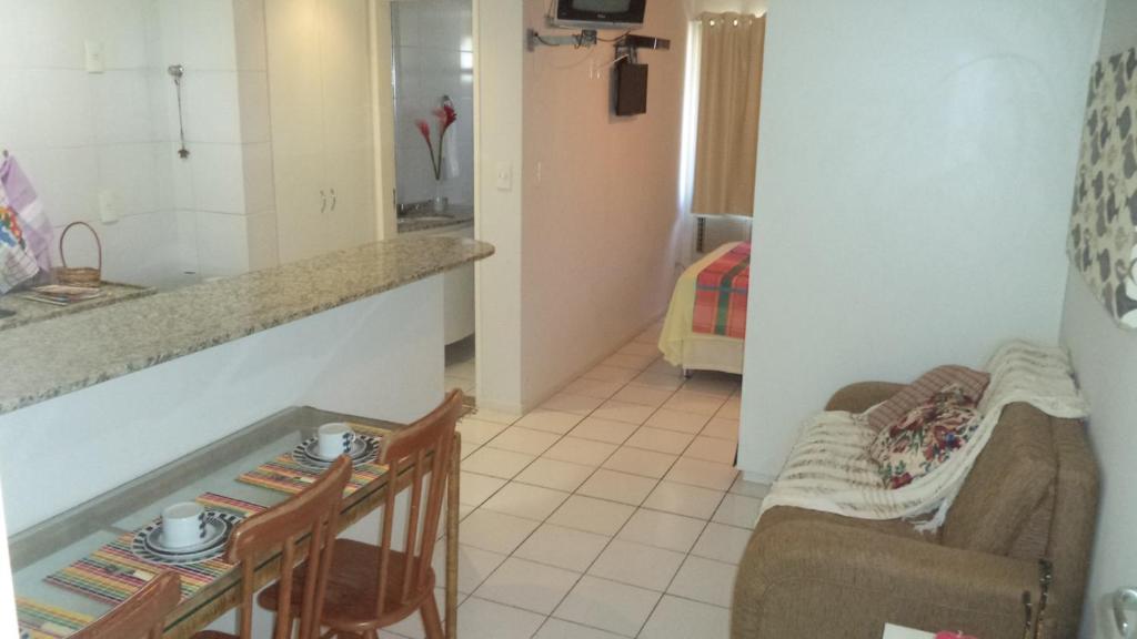 a kitchen and a living room with a couch and a table at Apartamento Temporada Maceió in Maceió