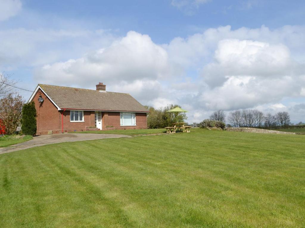 a brick house with a large lawn in front of it at North Farm Bungalow in Horsley