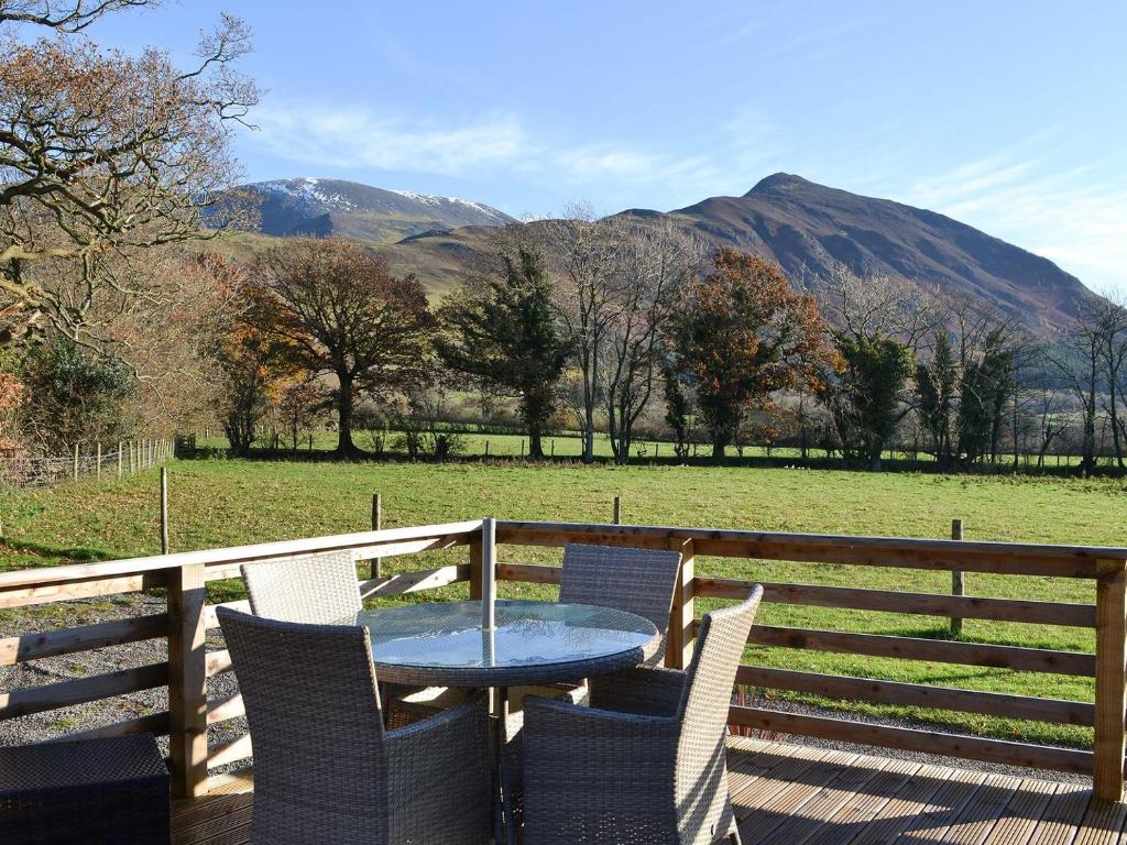 a table and chairs on a deck with mountains in the background at Watches - Uk13544 in Bassenthwaite