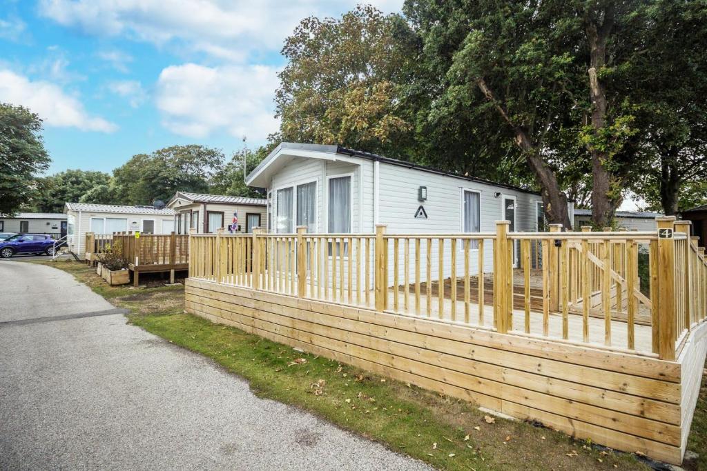 a wooden fence in front of a house at Beautiful Caravan With Decking At Azure Seas In Suffolk, Sleeps 6 Ref 32004az in Lowestoft