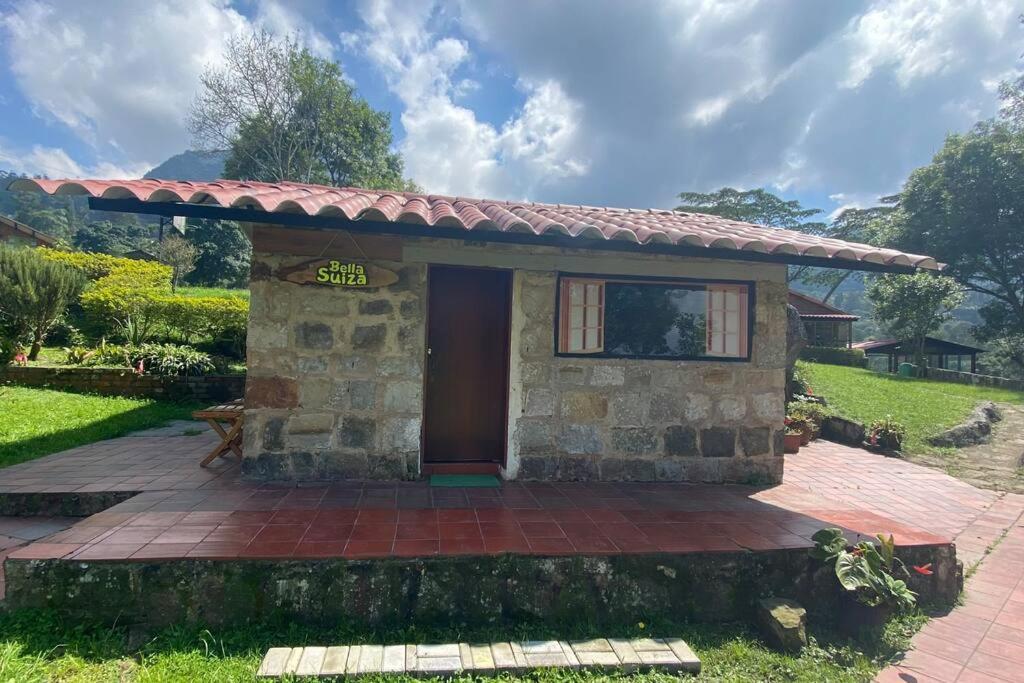 a small stone house with a red door at Confortable cabaña para que disfrute con su pareja in Santandercito