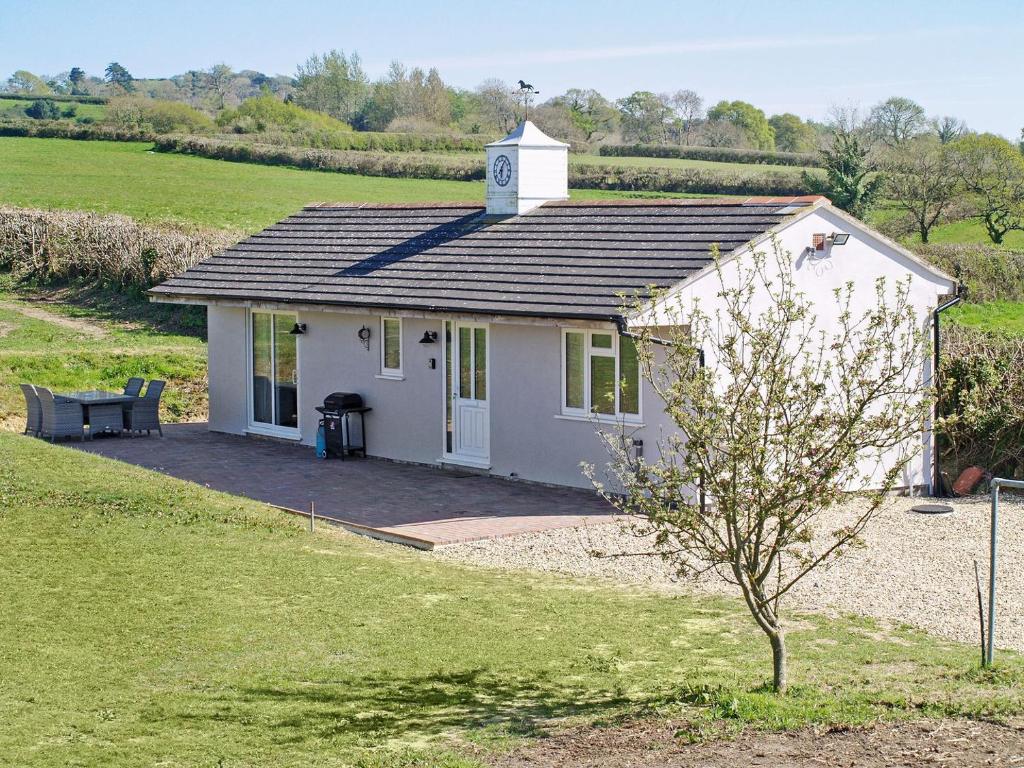 a small white house with a clock tower on it at The Stables At Greenview in Winsham