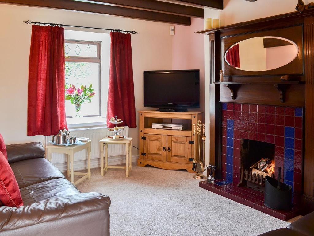 a living room with a fireplace and a tv at Puffin Cottage in Bempton