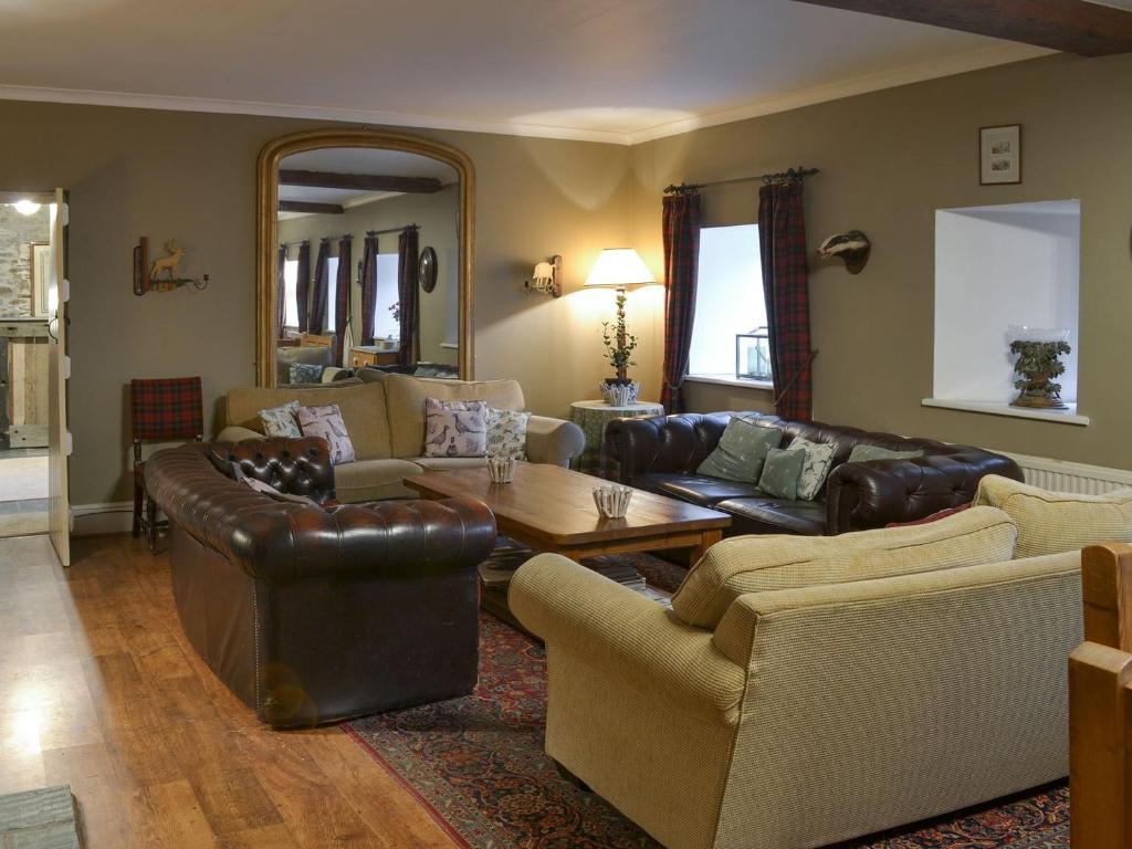 a living room with leather furniture and a table at The Shooting Lodge in Saint Mabyn