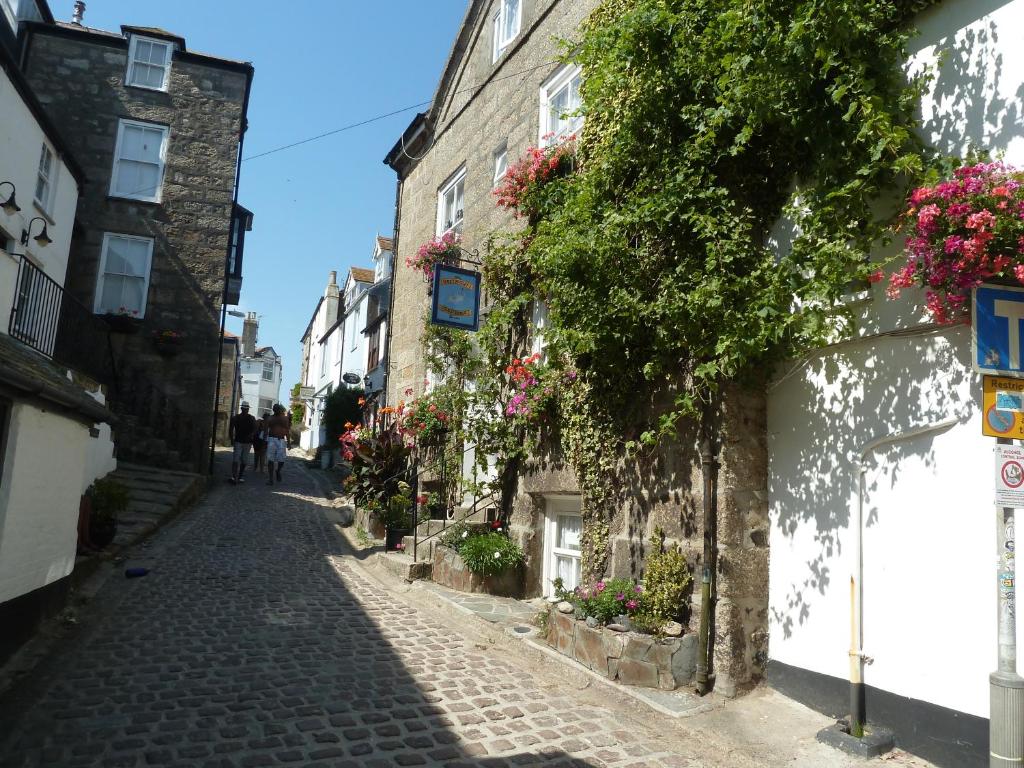 a cobblestone street in an old town with flowers at Grey Mullet Guesthouse in St Ives