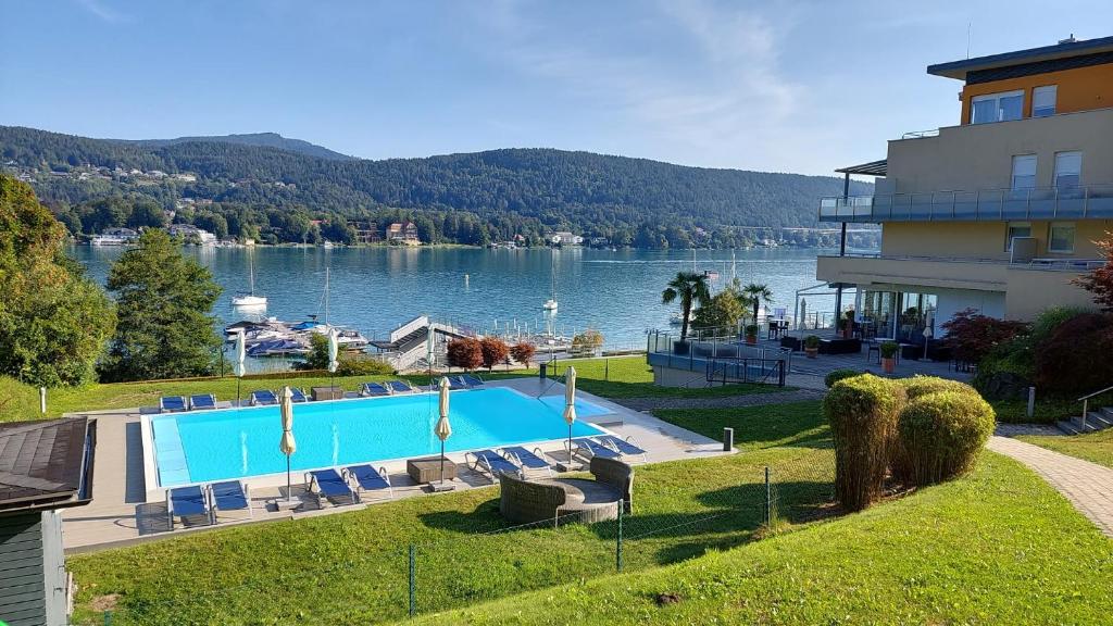 una piscina di fronte a un edificio con un lago di Seepark Velden a Velden am Wörthersee