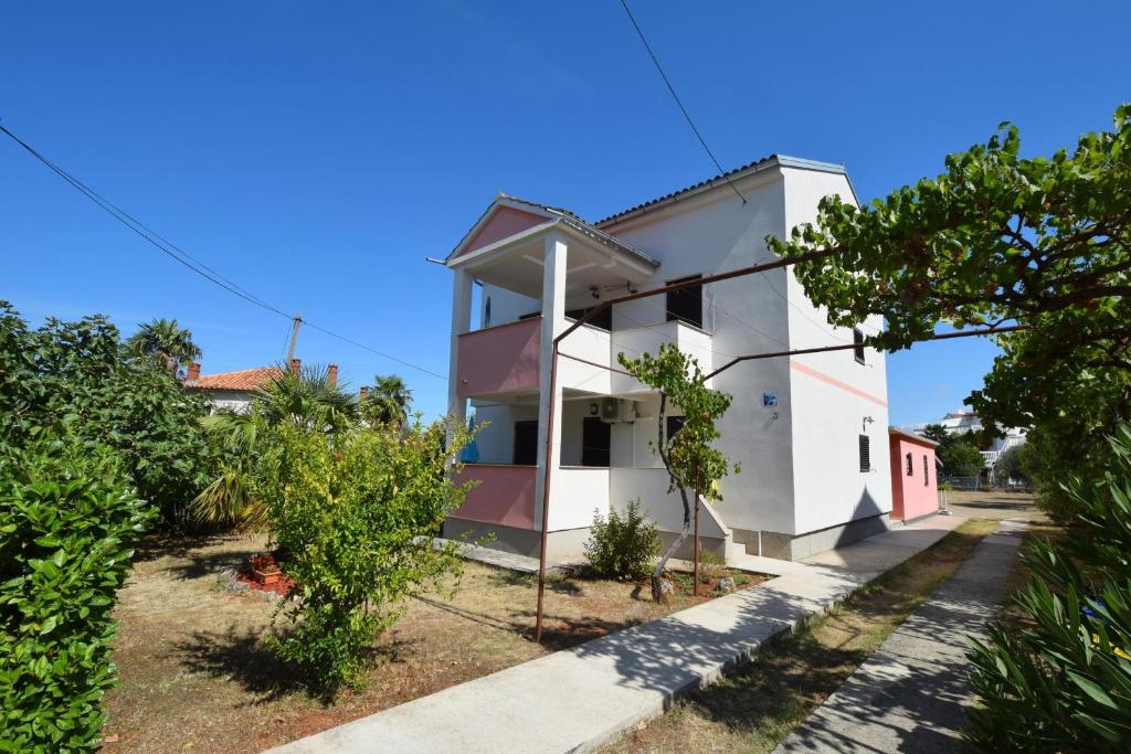 uma casa branca com um telhado vermelho em Apartments Petrovic em Malinska