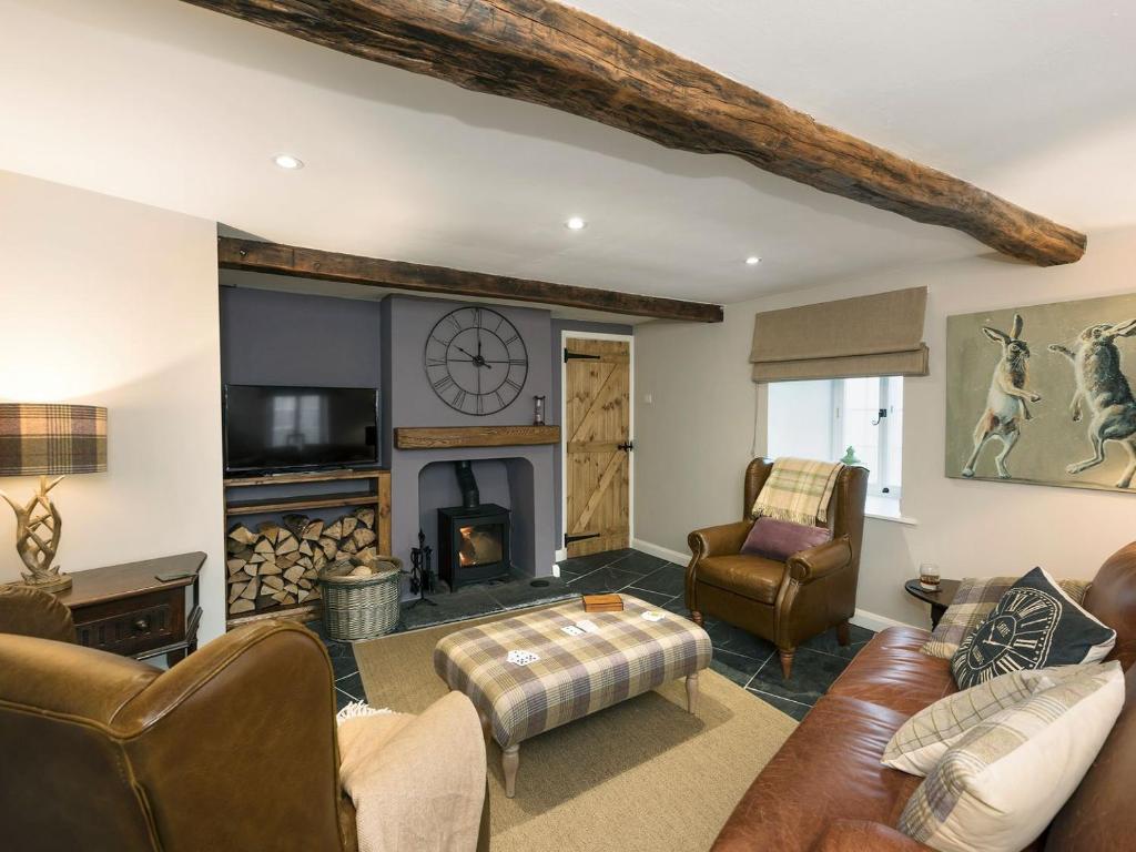 a living room with leather furniture and a fireplace at Crescent Cottage in Askham