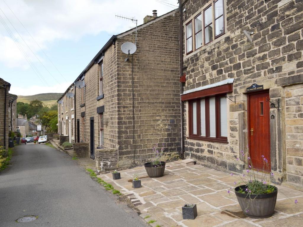 a brick building with a red door on a street at Weavers Houses in Hayfield