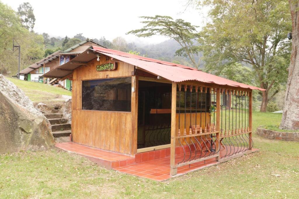 ein kleines Holzgebäude mit rotem Dach in der Unterkunft Cabañita en el Parque Natural Ecocenter in Santandercito