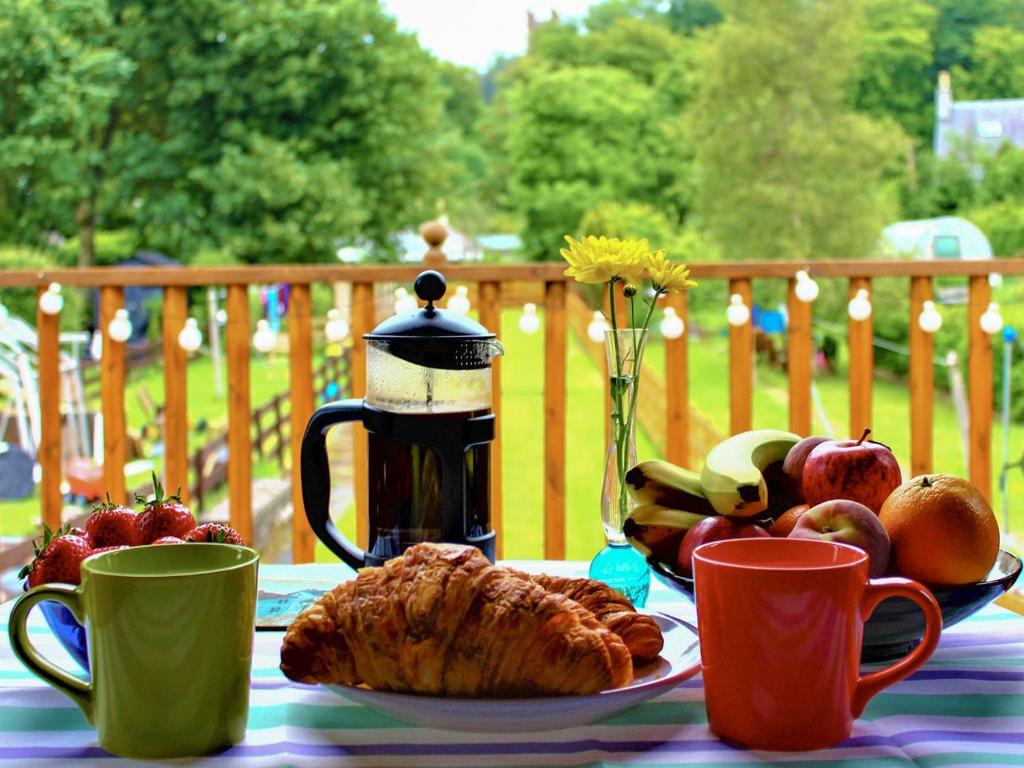 une table avec une assiette de fruits et des tasses à café dans l'établissement Curlew Cottage, à Creetown