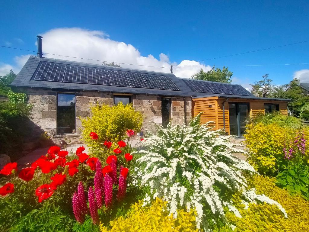ein Haus mit Sonnenkollektoren auf dem Dach in der Unterkunft Braeside Cottage - Adorable 2 Bedroom Eco-Friendly Character Cottage in Pitlochry