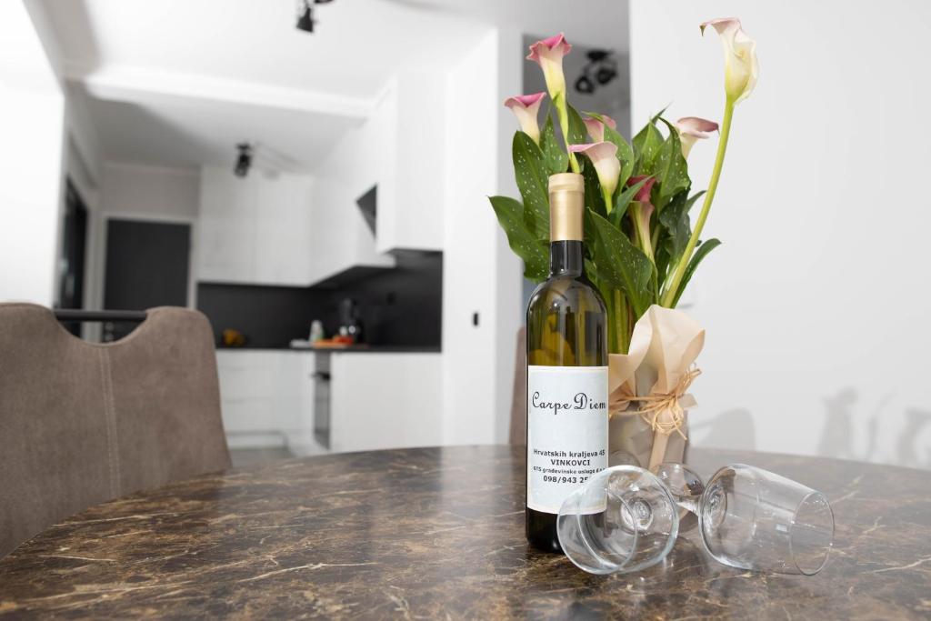 butelka wina na stole z wazonem kwiatów w obiekcie Carpe Diem w mieście Vinkovci