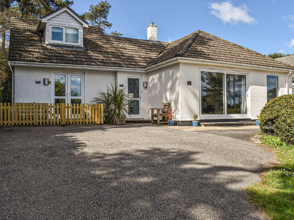 a white house with a wooden fence and a driveway at Caddie - Uk11038 in Carlyon Bay