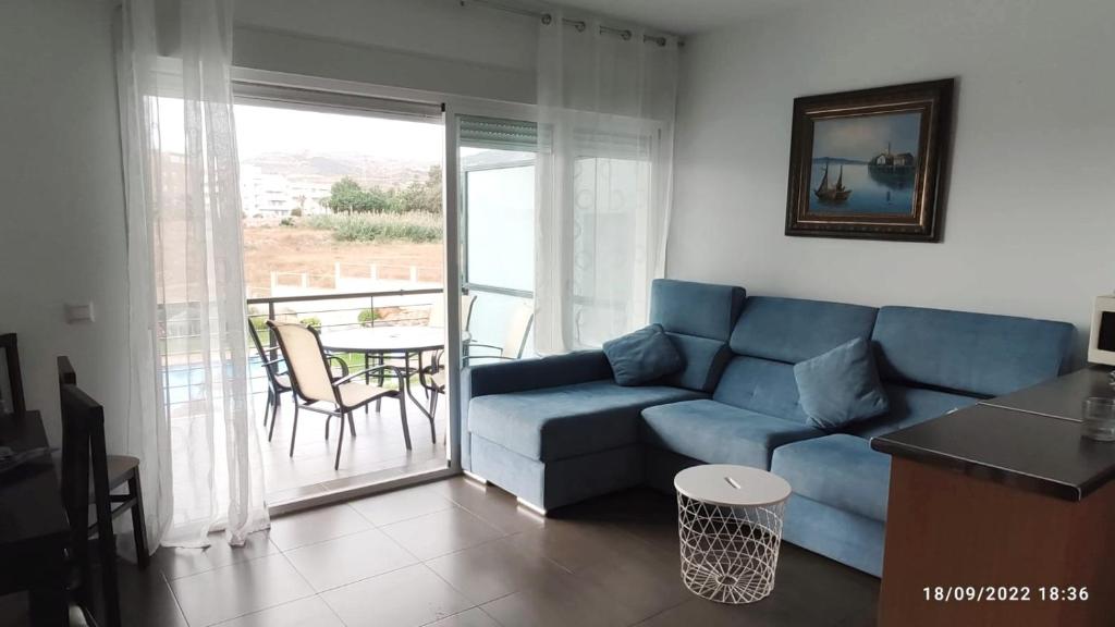 a living room with a blue couch and a balcony at Apartamento Jardines del Campanario in Torrox