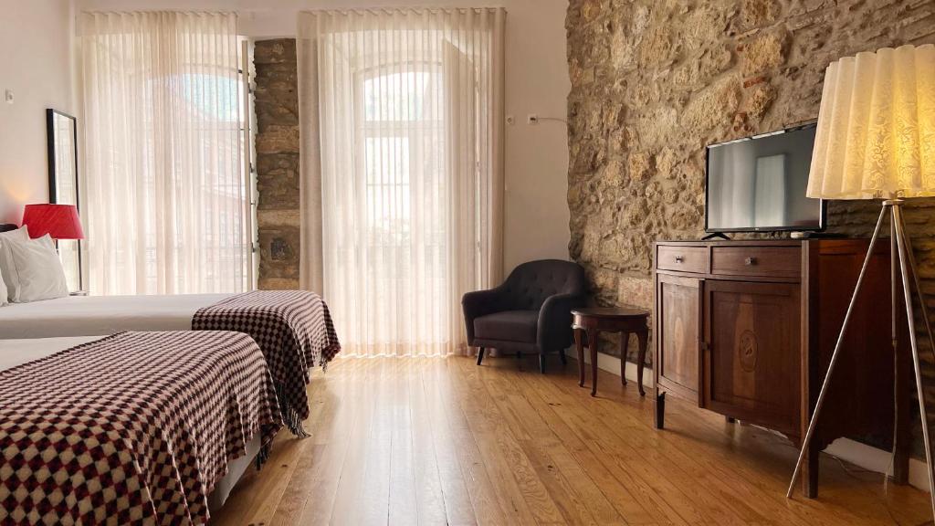 a bedroom with a bed and a flat screen tv at Casa do Bairro by Shiadu in Lisbon