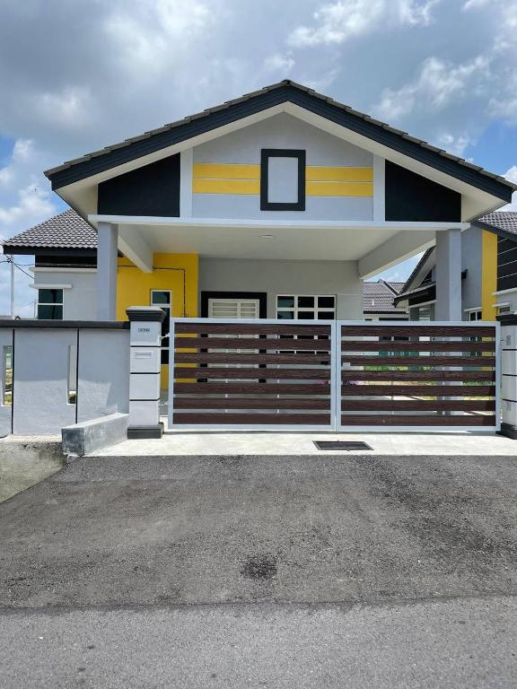 une maison avec une clôture devant elle dans l'établissement Bungalow Homestay Jasin, à Malacca