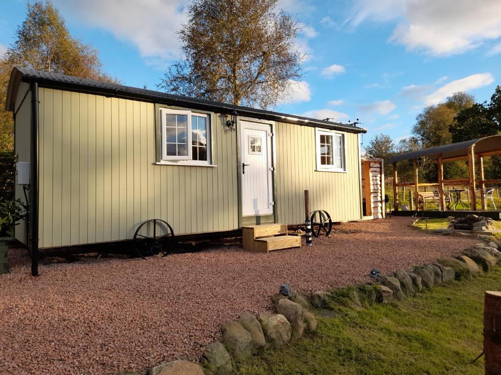 a small yellow tiny house on a gravel yard at Sunset View Shepherds Hut in Dalmally