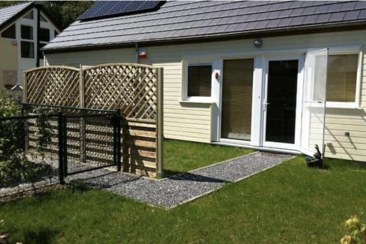 a fence in front of a house with a door at La clairière du lac, le bungalow de l'écureuil in Froid-Chapelle