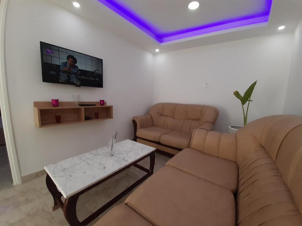 uma sala de estar com um sofá e uma televisão na parede em Dar salah em Hammamet