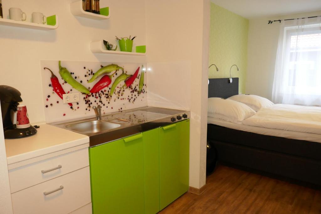 a kitchen with green cabinets and a sink and a bed at Appartmentanlage/Ferienhaus Handewitt in Handewitt