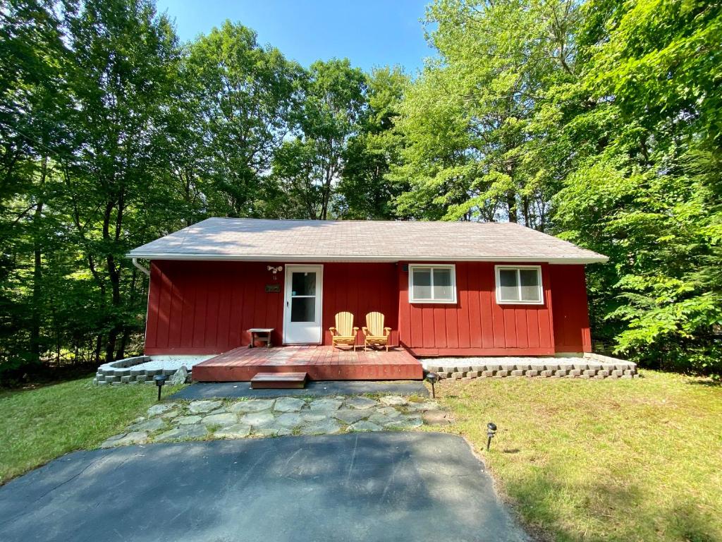 a red house with two chairs in front of it at Escape to a 3-Bedroom Cabin in Lower Catskills in Woodridge